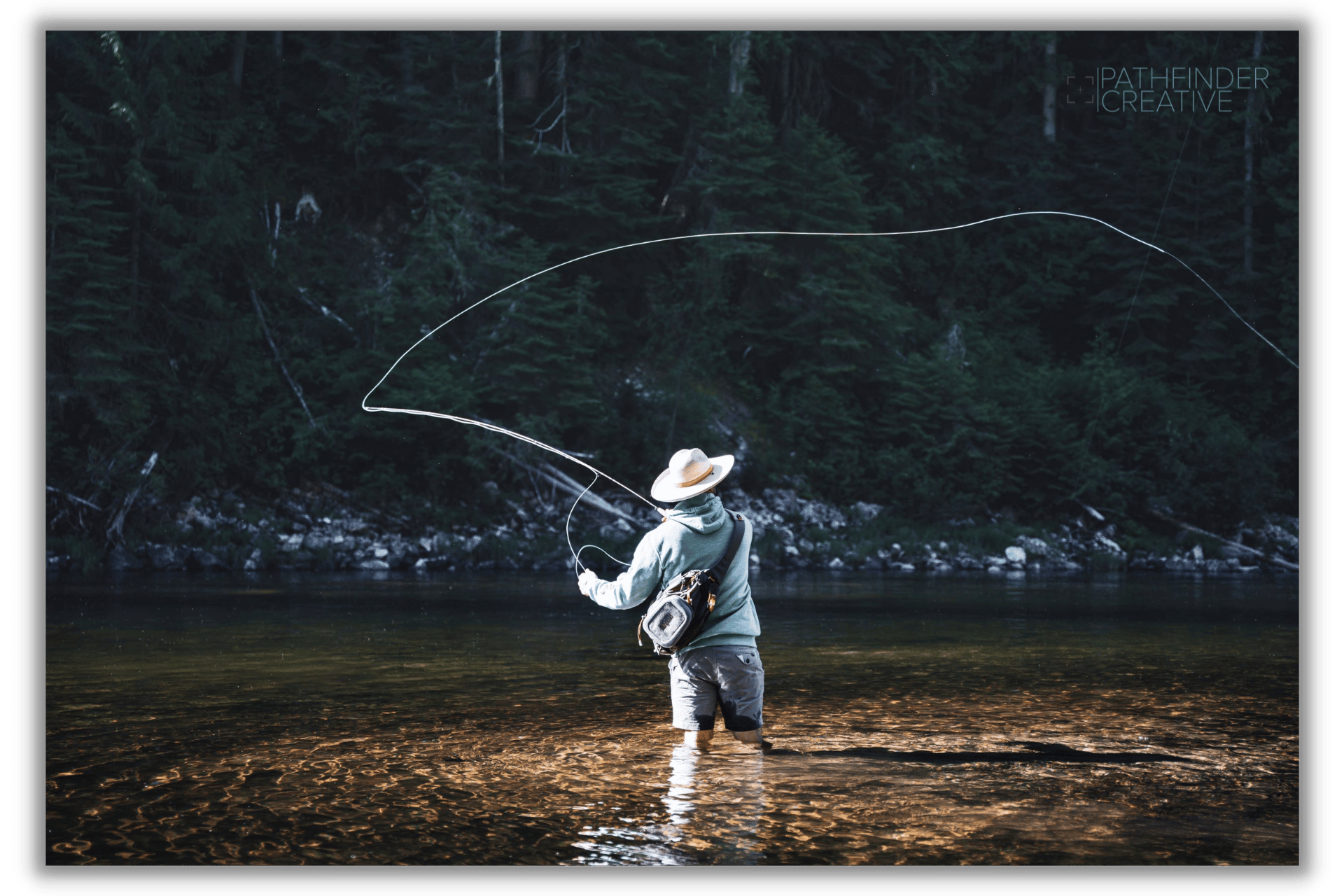 man fly fishing in deep green river with forest