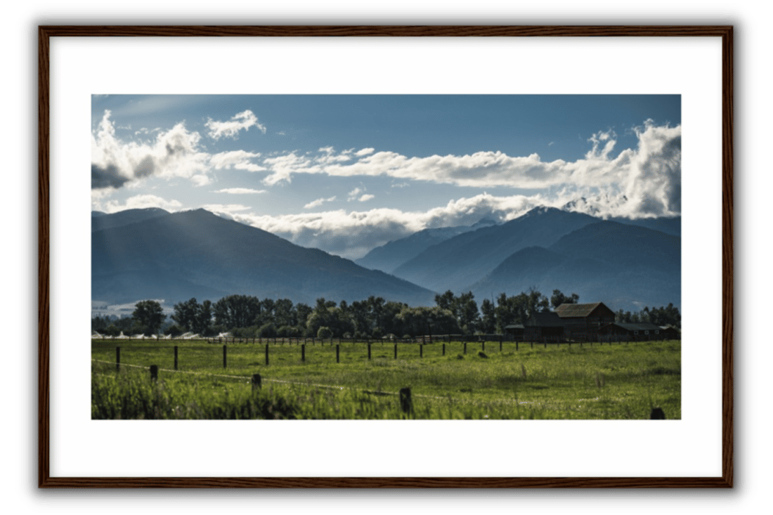 summer in the valley with mountains, green fields, white clouds, blue skies