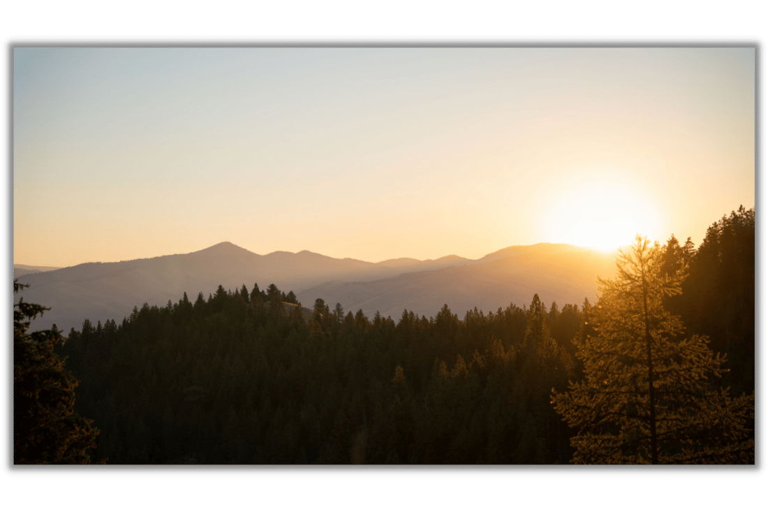 canvas print of forested mountains and an orange sunrise over the mountains