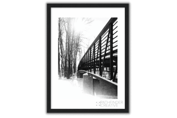 metal bridge over a creek with trees and snow in the winter black and white