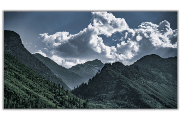 majestic green forested mountains with blue sky and white clouds
