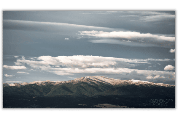 beautiful green mountains with snow capped peaks, blue sky, white clouds