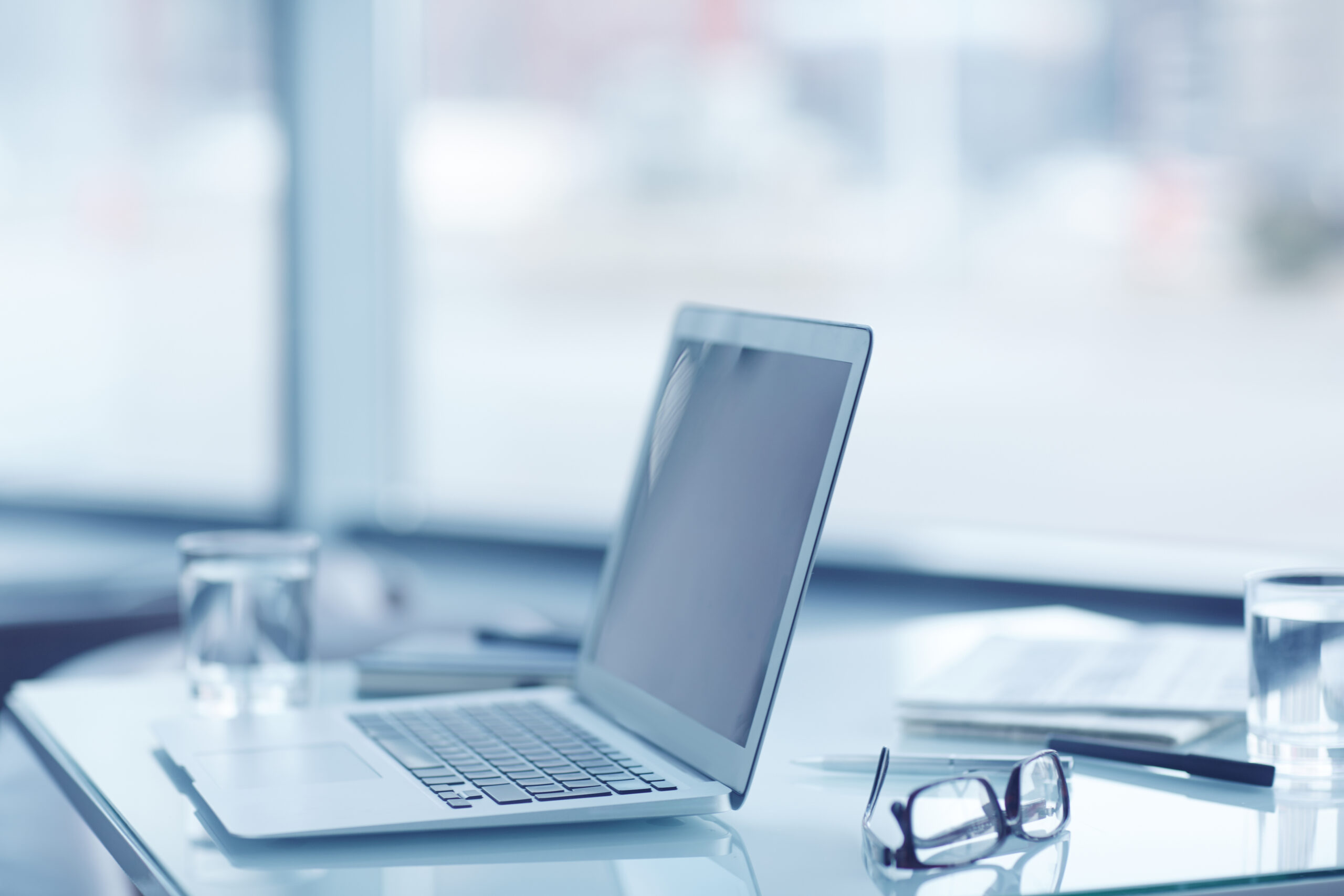 Laptop, eyeglasses and pens at abandoned workplace